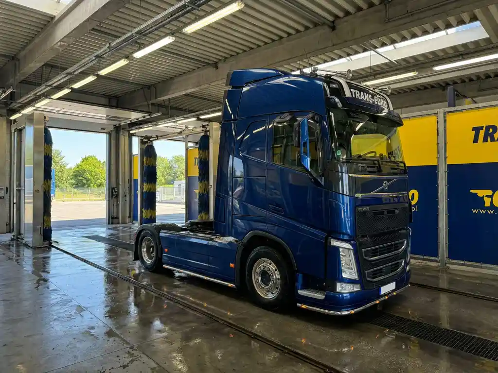 Blauwe Europese vrachtwagen in moderne wasstraat met chromen details, industriële verlichting en open deuren