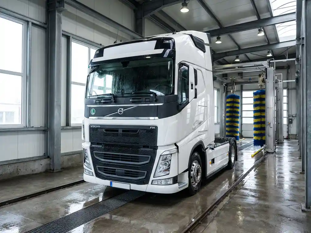 Witte Europese vrachtwagen in moderne wasstraat met industriële verlichting en blauwe en gele wasapparatuur